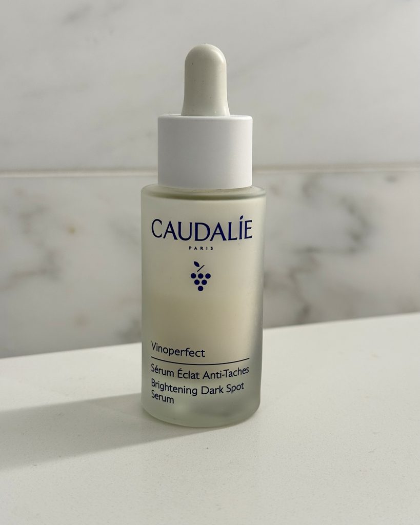 Caudalie Vinoperfect Serum bottle on a marble background