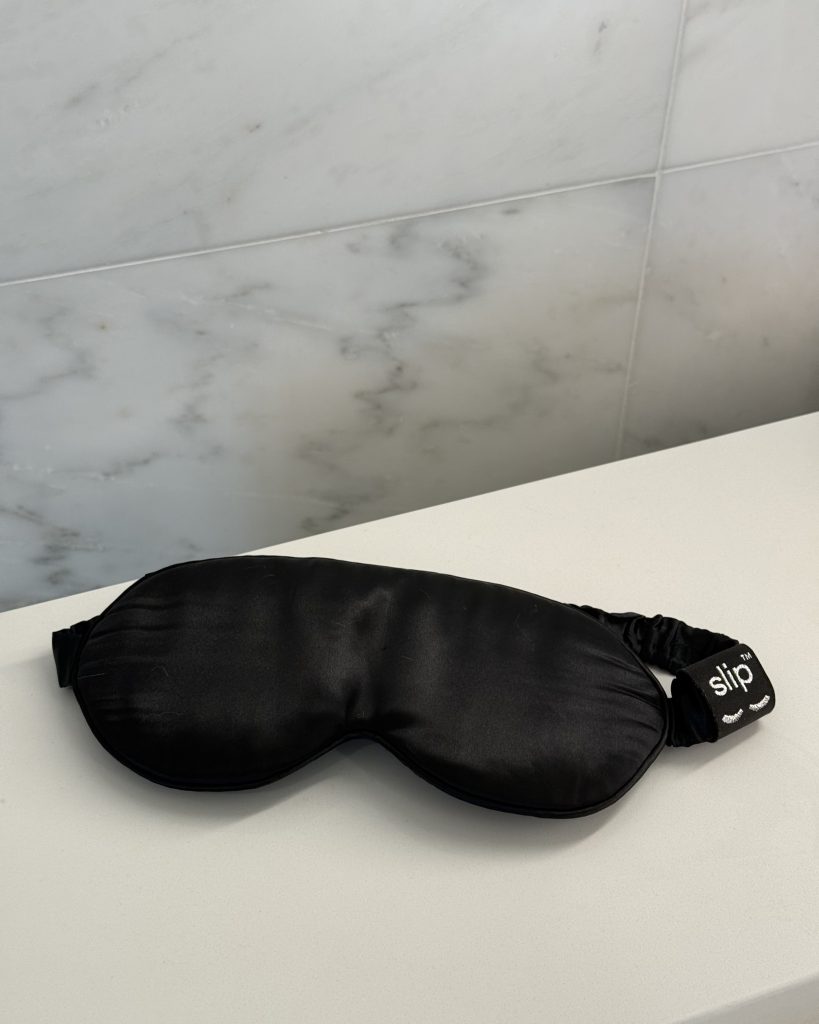 Black Slip silk contour sleep mask laid flat on marble
